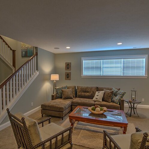 A living room with couches and a stairway designed by a Luxury custom home builder in Westfield Indiana.