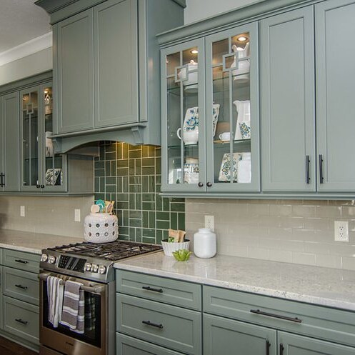 A kitchen with green cabinets and a stove, customized by a luxury custom home builder in Carmel Indiana.