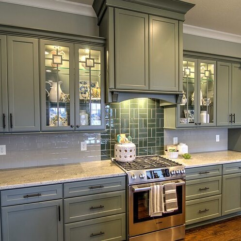 A kitchen with green cabinets and granite counter tops, designed by a luxury custom home builder in Westfield Indiana.