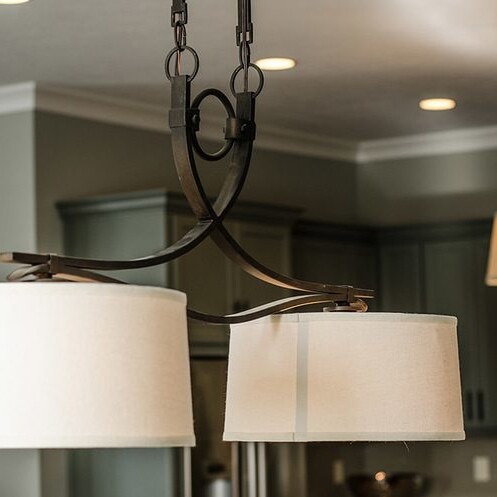 A kitchen with a light fixture hanging over it in a custom home for sale in Carmel Indiana.