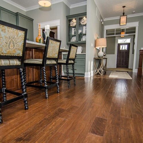 A kitchen with hardwood floors and bar stools in a custom home for sale in Carmel, Indiana.