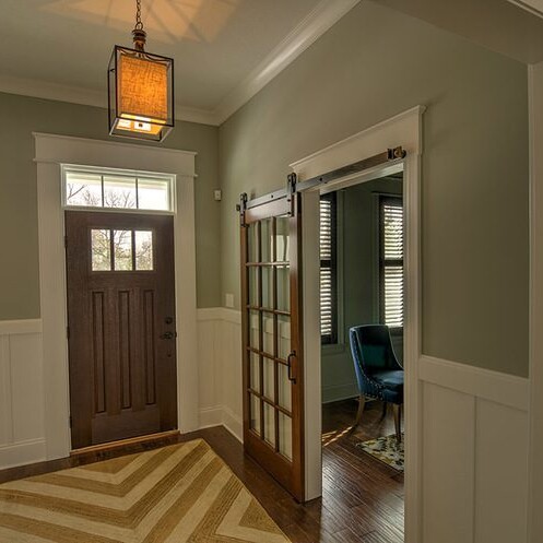 A hallway with a door and a chevron rug, designed by a luxury custom home builder in Carmel Indiana.