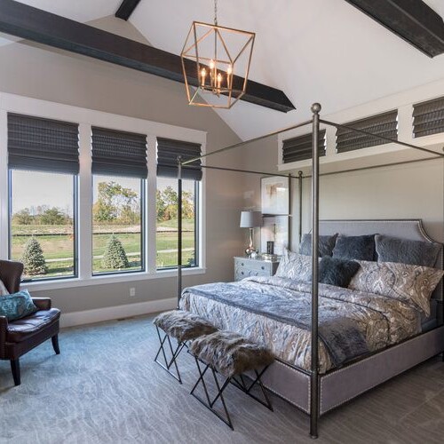 A bedroom with a four poster bed and a vaulted ceiling in a custom home builder carmel indiana.