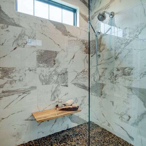 A stunning marble shower featuring a luxurious wooden bench.