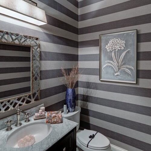 A bathroom with gray and white striped wallpaper in a custom home builder carmel Indiana.