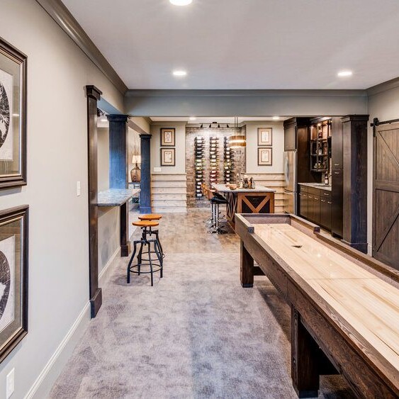 A game room with a shuffleboard table and framed pictures, located in a custom home in Westfield, Indiana.