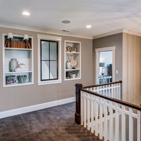 A hallway with a light fixture and bookshelves in a custom home built by a new home construction company in Carmel, Indiana.