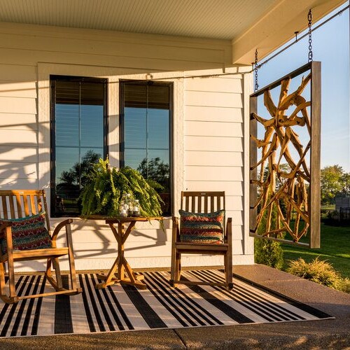 A porch with two rocking chairs and a table, perfect for relaxing and enjoying the outdoors.