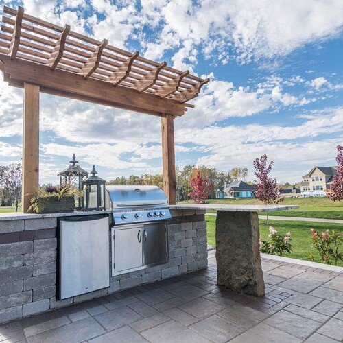 A stunning outdoor kitchen with a pergola and grill, perfect for enjoying the outdoors in the comfort of a new custom home in Westfield, Indiana.