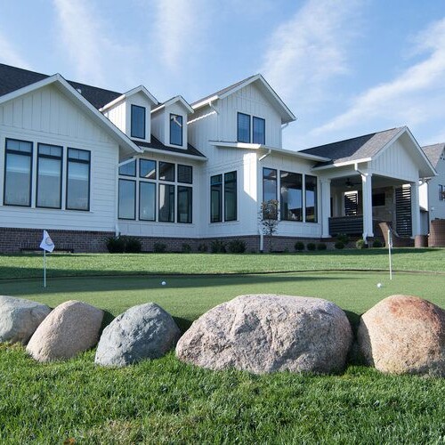 A custom home with a putting green in front of it for sale in Carmel, Indiana.