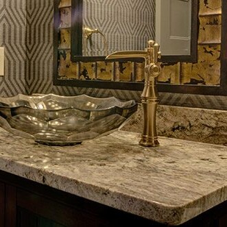 A bathroom with a gold sink and mirror in a custom home.