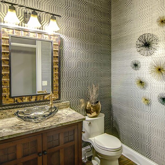 A bathroom with a toilet, sink and mirror designed by a custom home builder in Indianapolis Indiana.