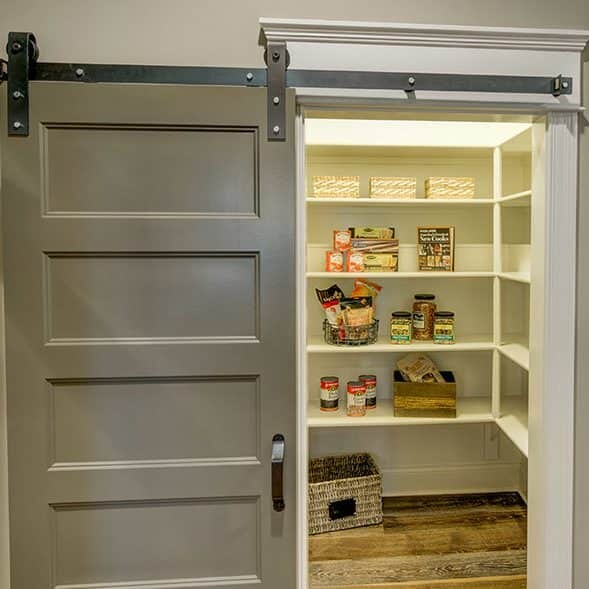 A pantry with a sliding barn door, offered by a Custom Home Builder in Carmel Indiana.