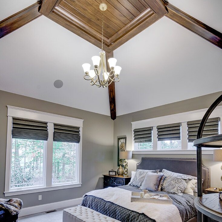 A bedroom with wood ceilings and a bed, found in custom homes for sale in Carmel Indiana.