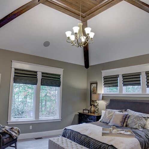 A bedroom with a vaulted ceiling and a chandelier, built by a Custom Home Builder in Fishers Indiana.
