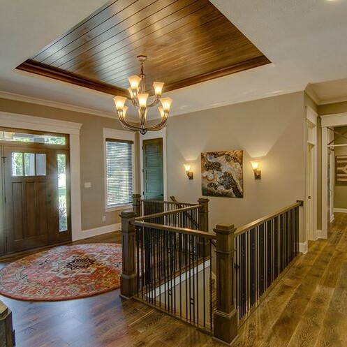 A hallway with hardwood floors and a chandelier in a custom home builder carmel indiana.