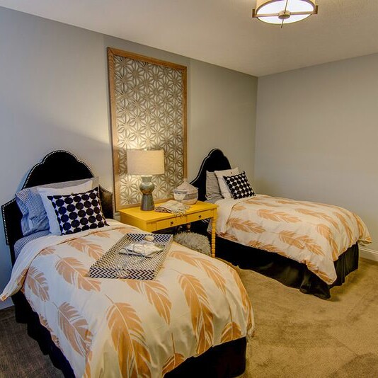 A bedroom with two beds and a lamp, designed by a Custom Home Builder in Carmel Indiana.