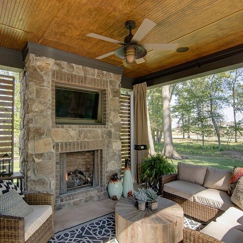 An outdoor living area with a fireplace and wicker furniture, perfect for custom home builders in Carmel, Indiana or individuals looking for homes for sale in Westfield, IN.