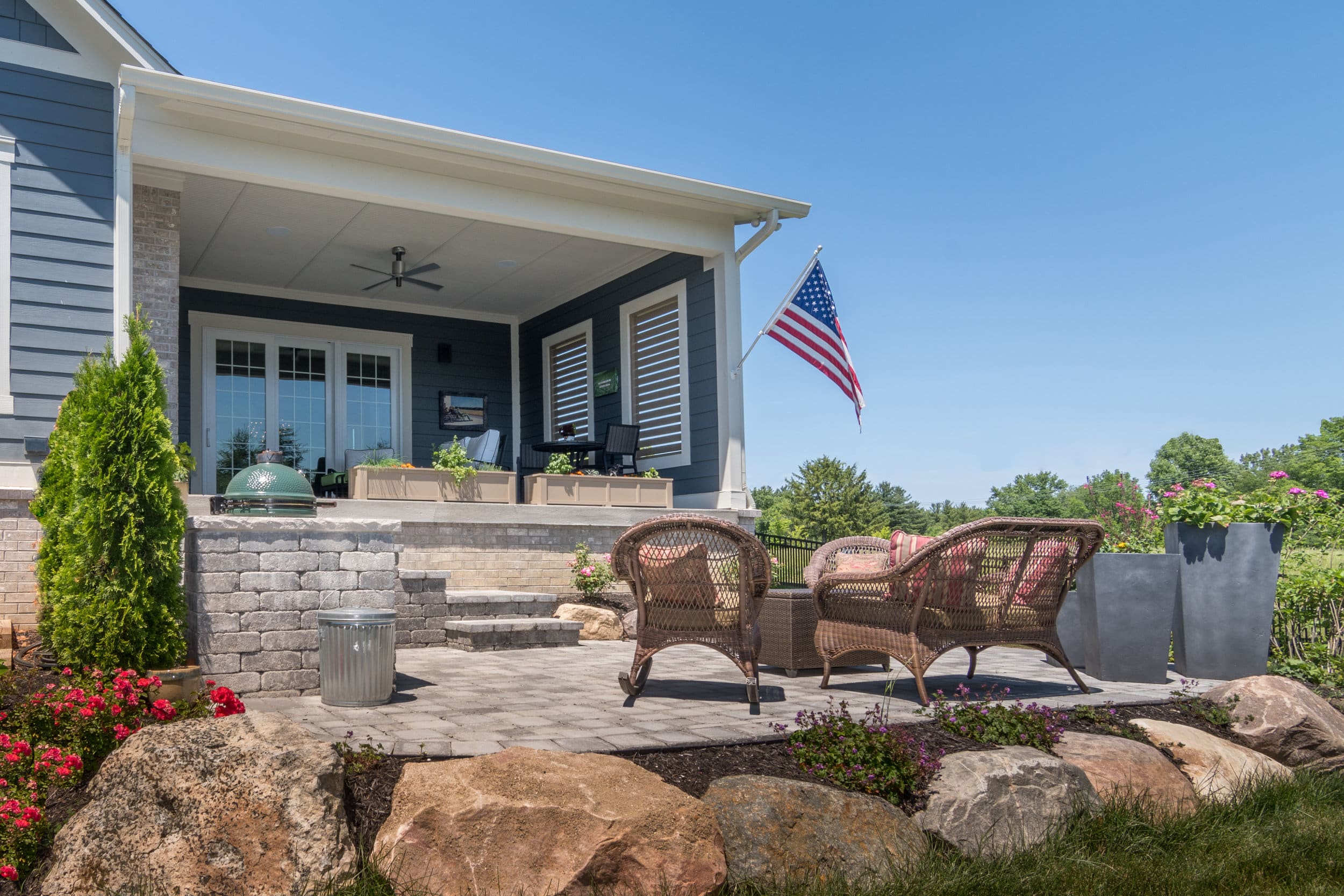 A custom home with an American flag on the front porch.