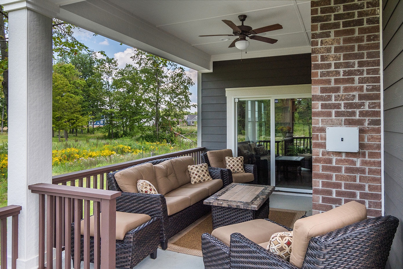 A porch with wicker furniture and a ceiling fan, designed and built by a Custom Home Builder Fishers Indiana.