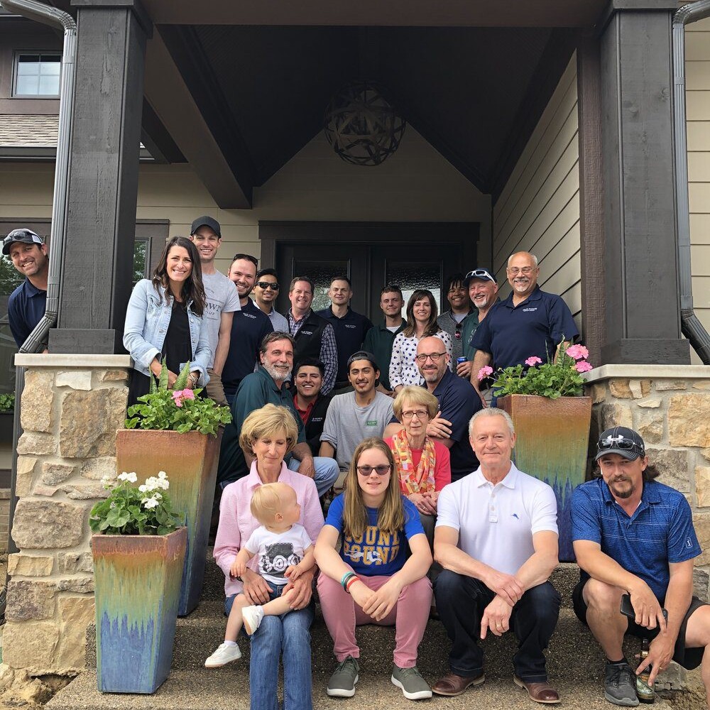 A group of people posing on the steps of a custom home in Carmel, Indiana.