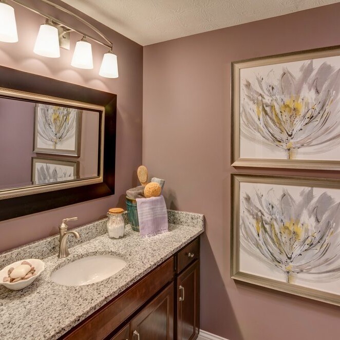 A bathroom with purple walls and framed artwork, designed by a Custom Home Builder in Indianapolis Indiana.