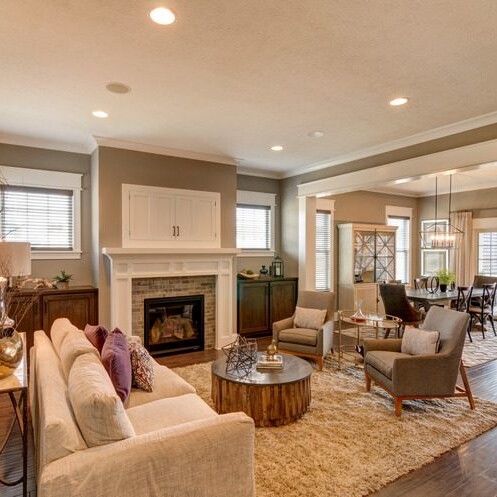 A living room with hardwood floors and a fireplace, part of a custom home in Carmel, Indiana.