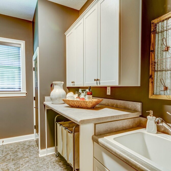A laundry room with white cabinets and a sink in a luxury custom home in Westfield, Indiana.