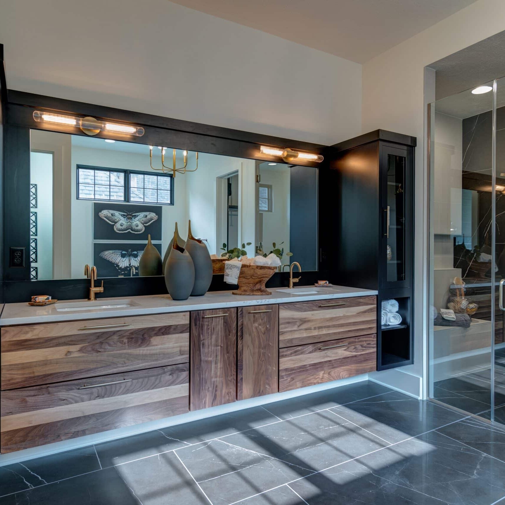 A bathroom with black cabinets and a glass shower.