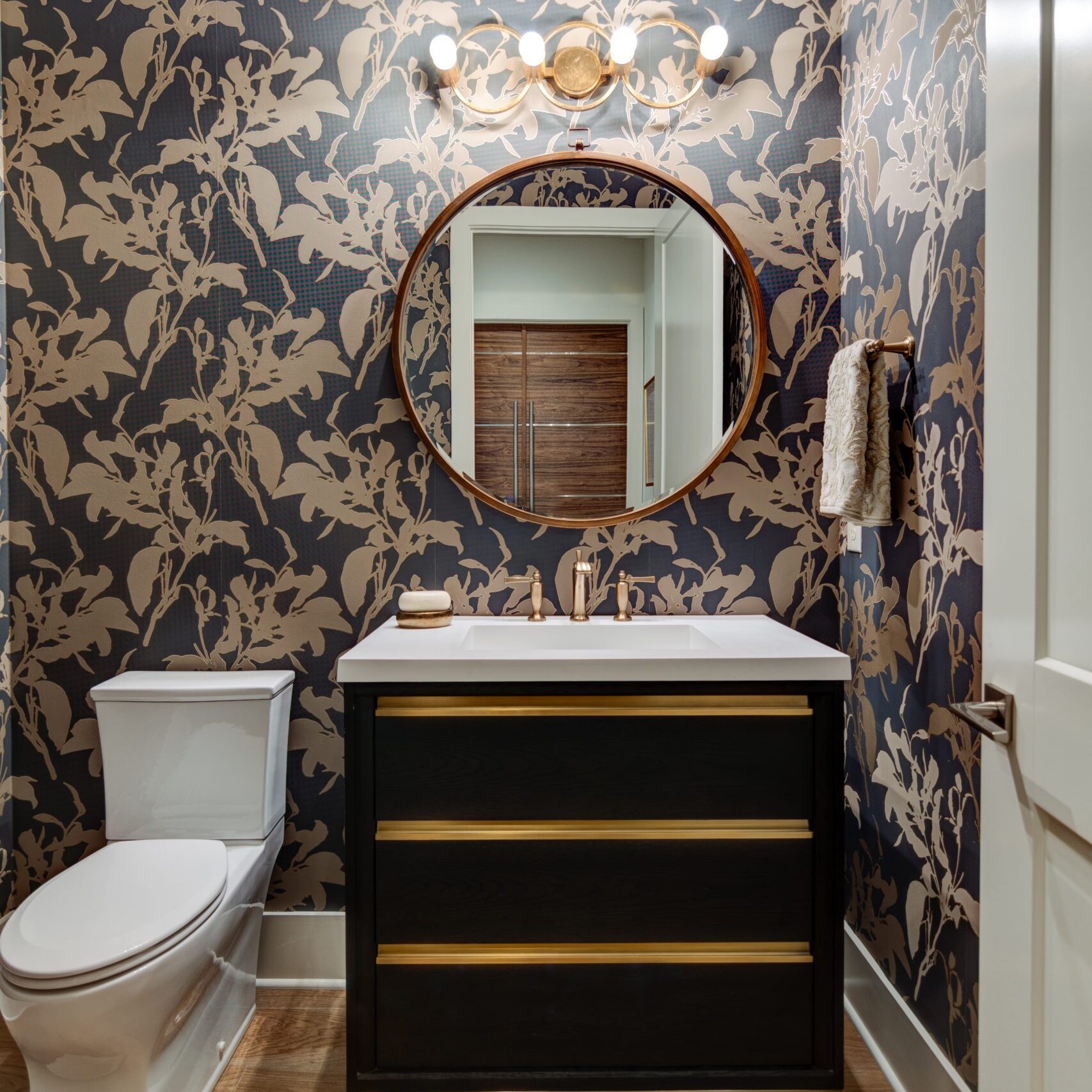 A black and gold bathroom with floral wallpaper.