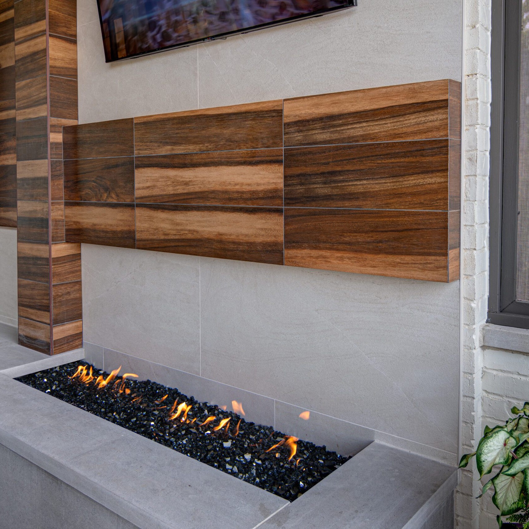 A modern outdoor fireplace with a tv above it.