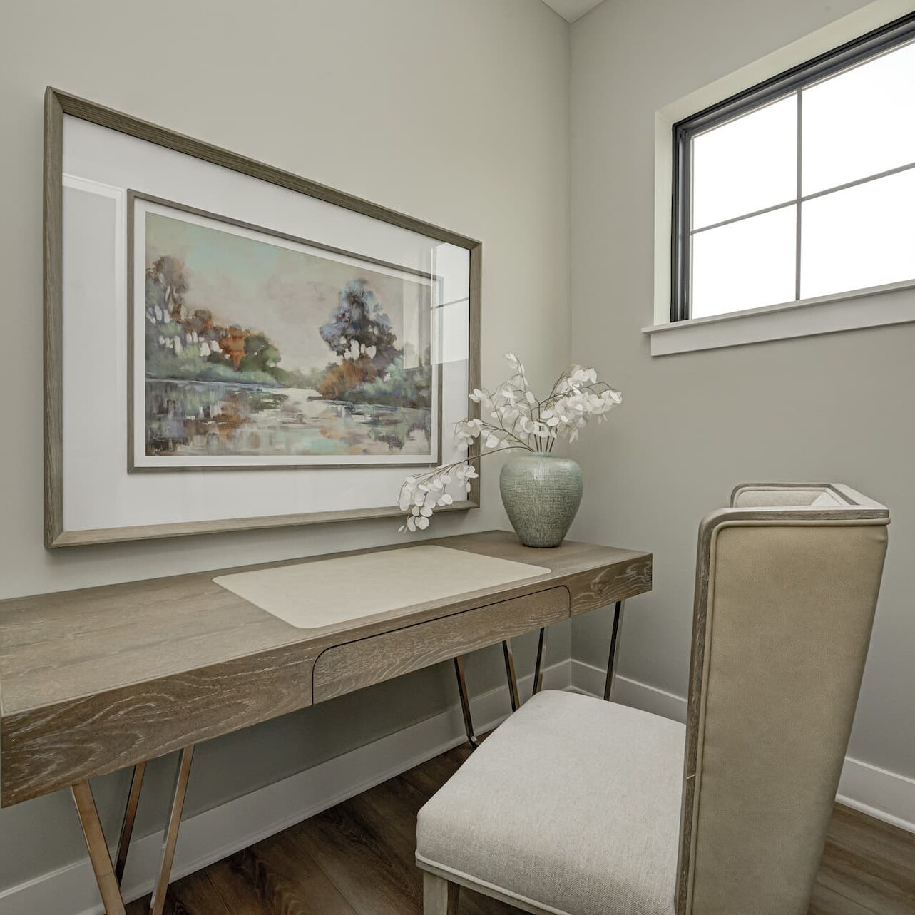 A room with a desk, chair and a painting designed by a Custom Home Builder in Fishers Indiana.