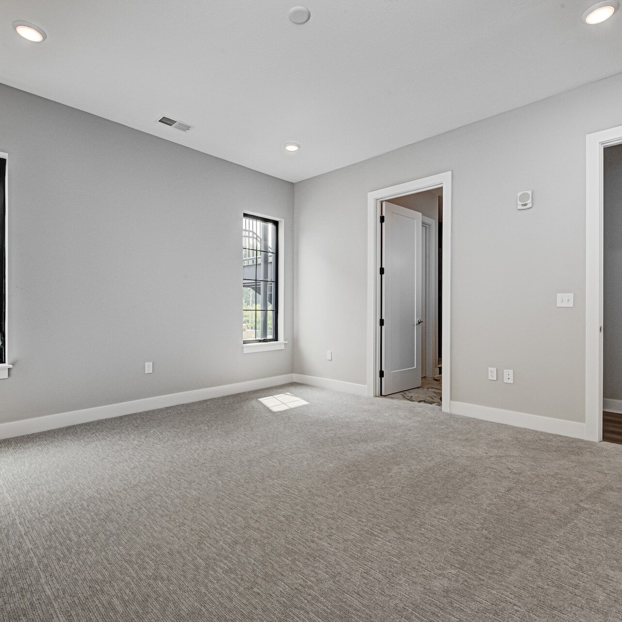 Empty bedroom with gray carpet and windows, designed by a Custom Home Builder in Carmel Indiana.