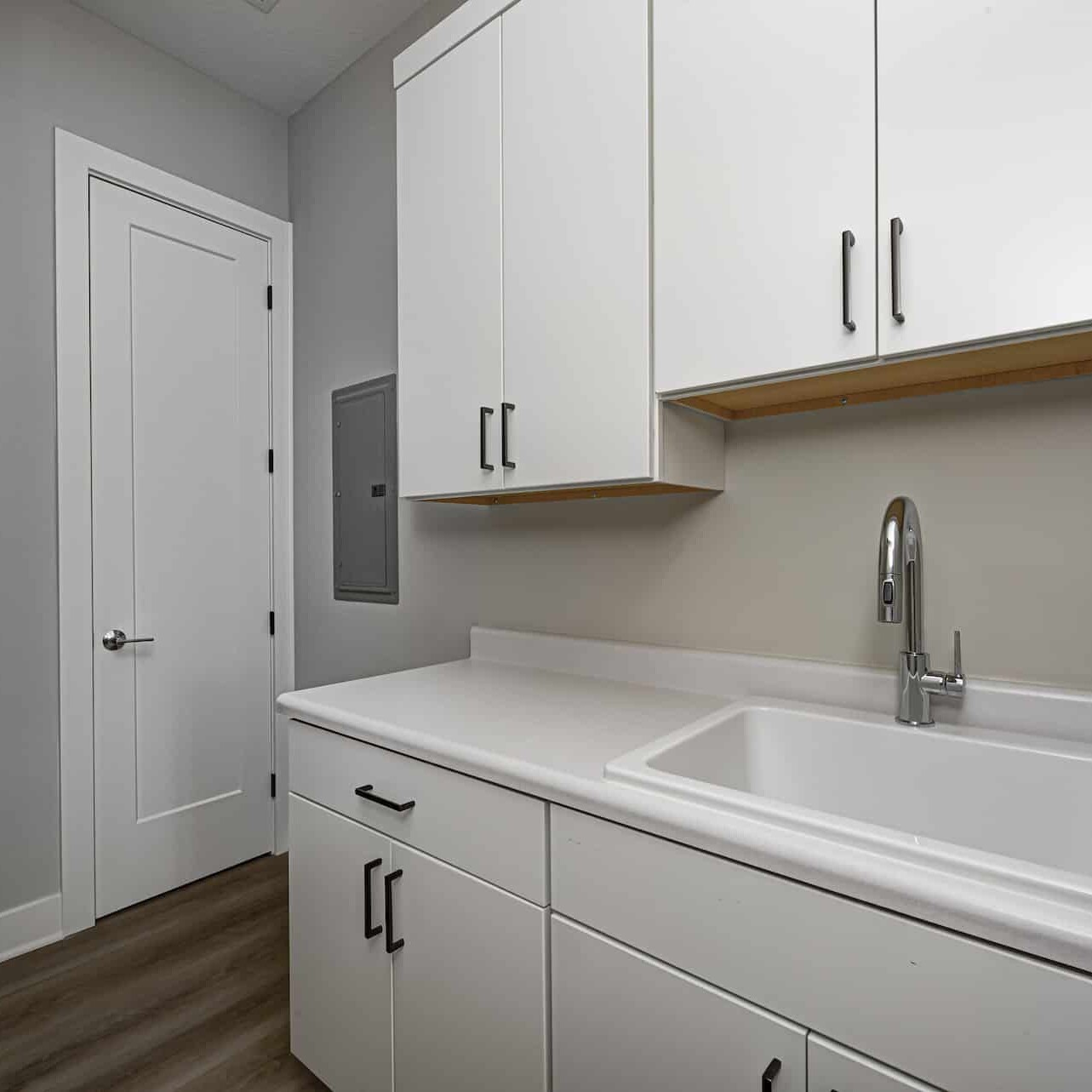 A laundry room with white cabinets and a sink designed by a Custom Home Builder in Carmel Indiana.