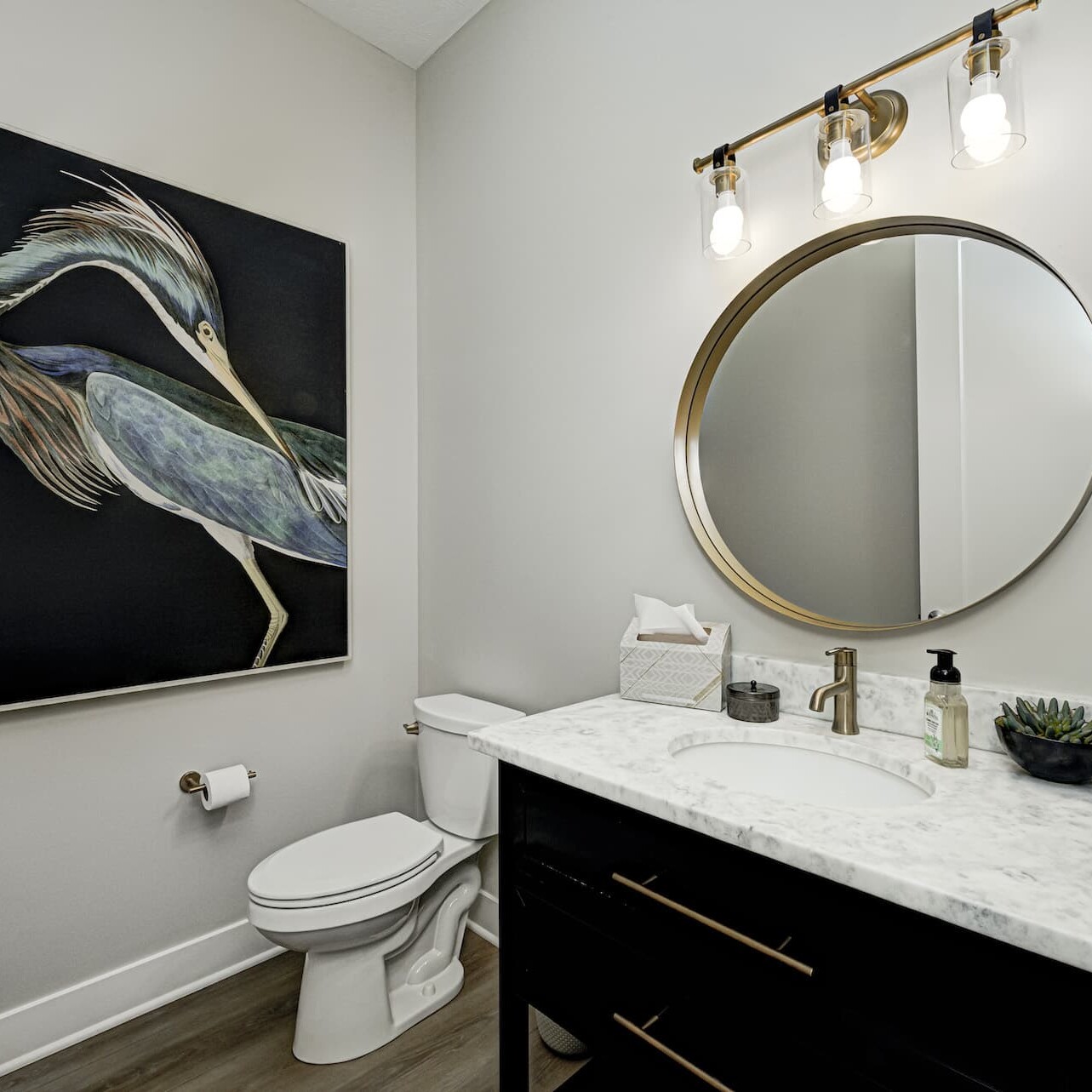 A black and gold bathroom with a painting on the wall, created by a Custom Home Builder in Carmel Indiana.