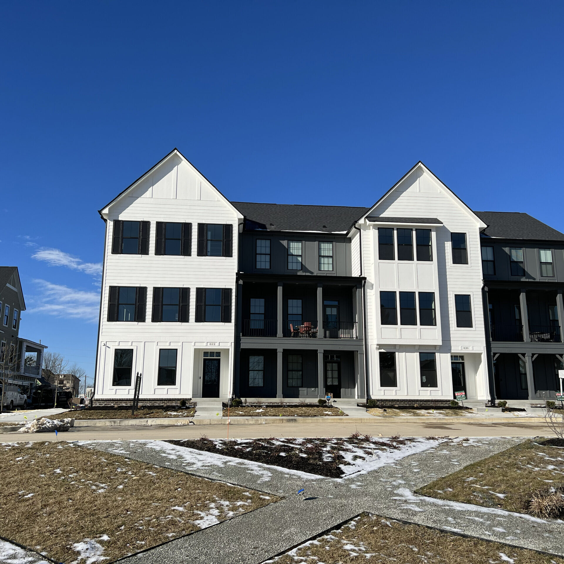 A group of custom townhouses in a neighborhood with snow on the ground.