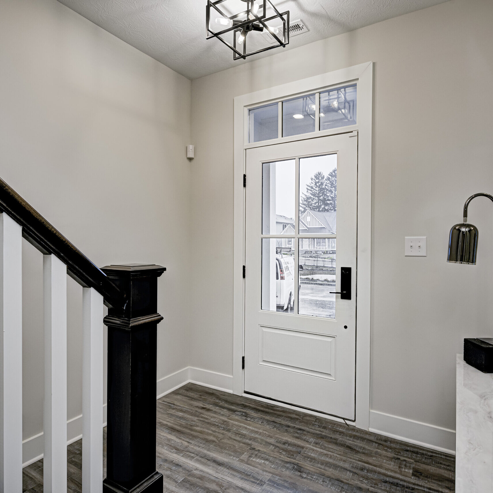 A hallway in a home with a white door and black railing, designed by a custom home builder.