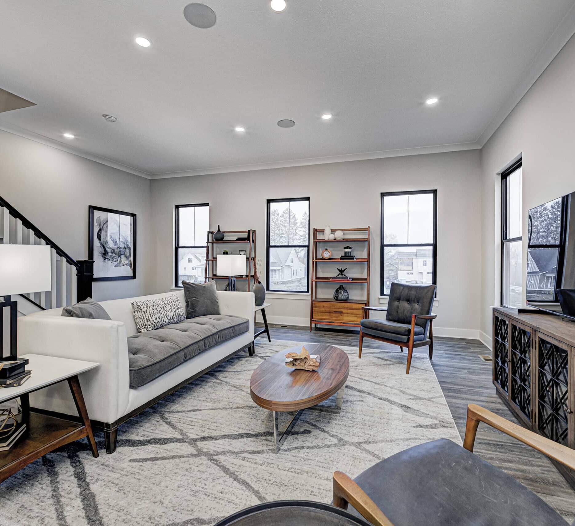 A cozy living room with comfortable couches and a stylish stairway, expertly crafted by a reputable custom home builder in Fishers Indiana.