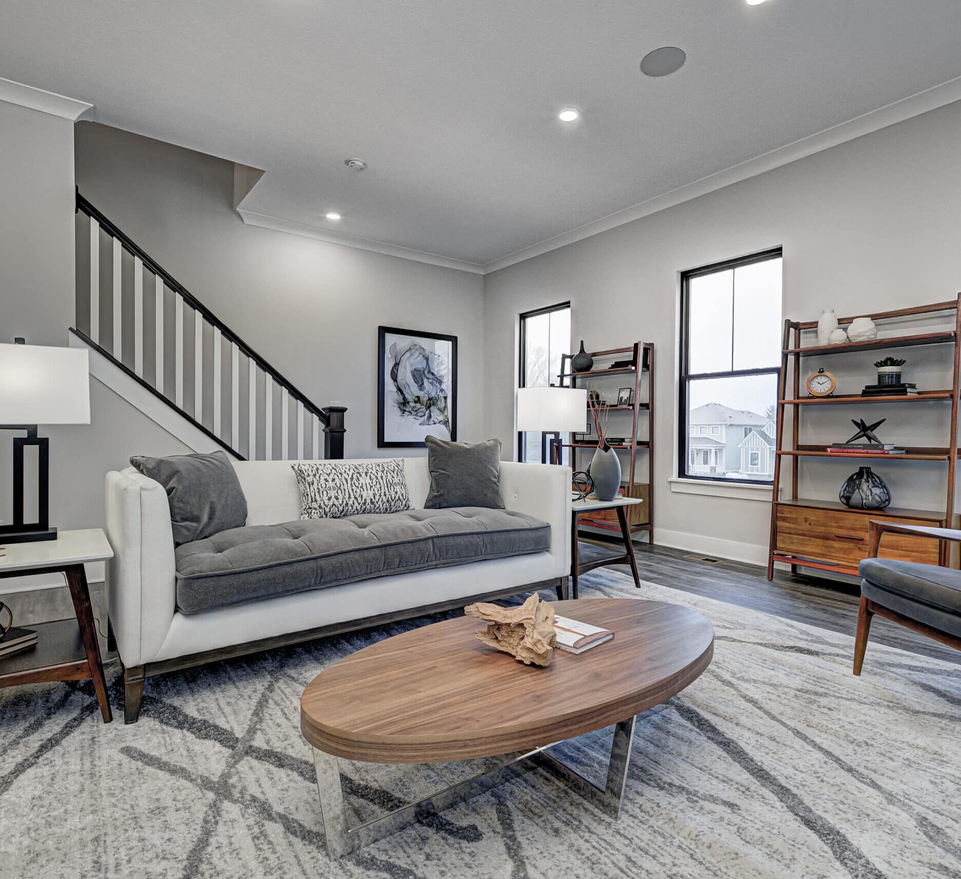A living room with gray furniture and a stairway designed by an Indianapolis Custom Homes builder.