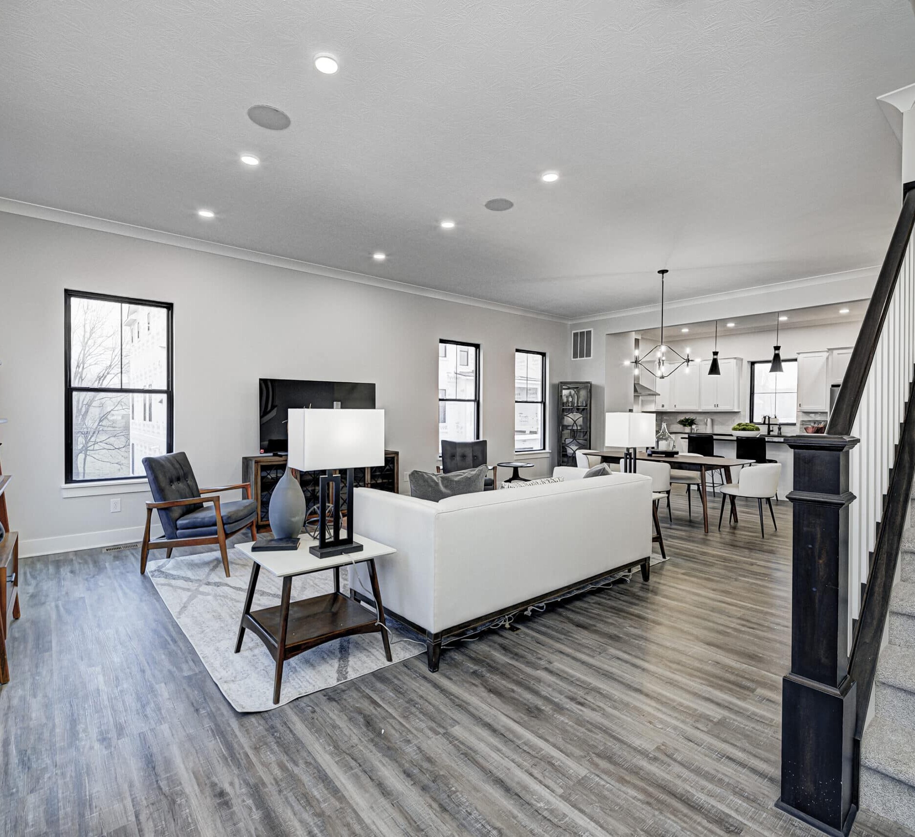 A custom home builder in Carmel, Indiana created a stunning living room with hardwood floors and a staircase.