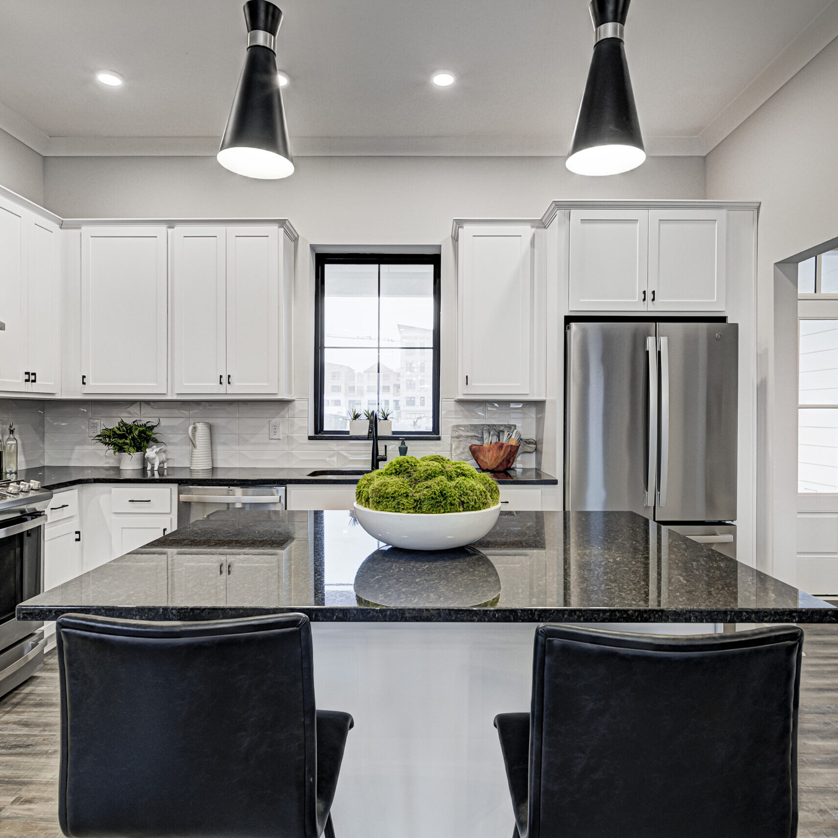 A custom kitchen with white cabinets and black counter tops.