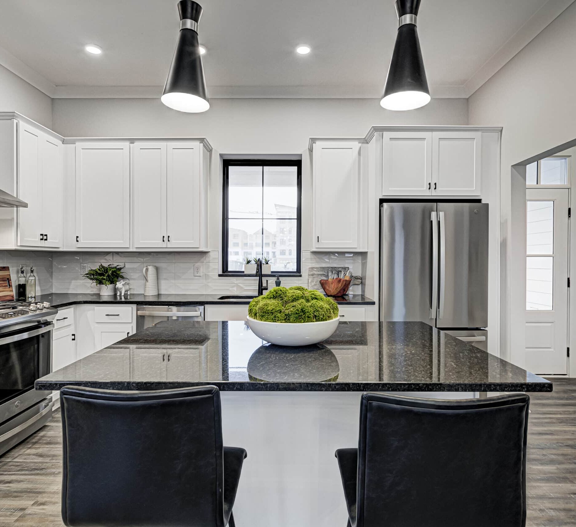 A custom kitchen with white cabinets and black counter tops.