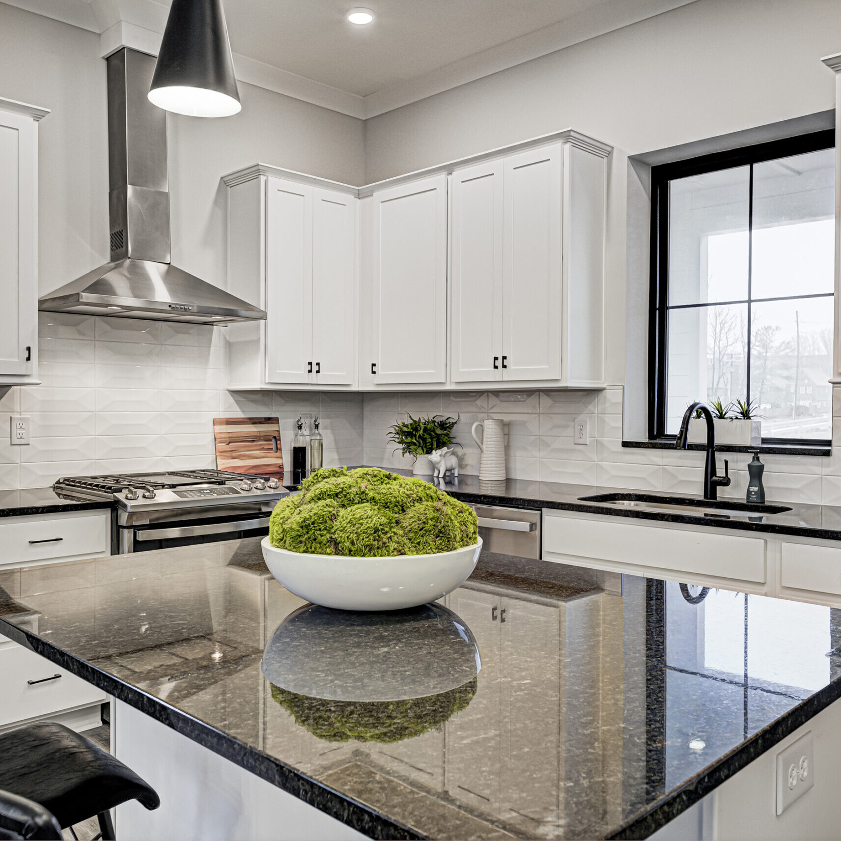 A kitchen with white cabinets and black counter tops, built by a Custom Home Builder Fishers Indiana.