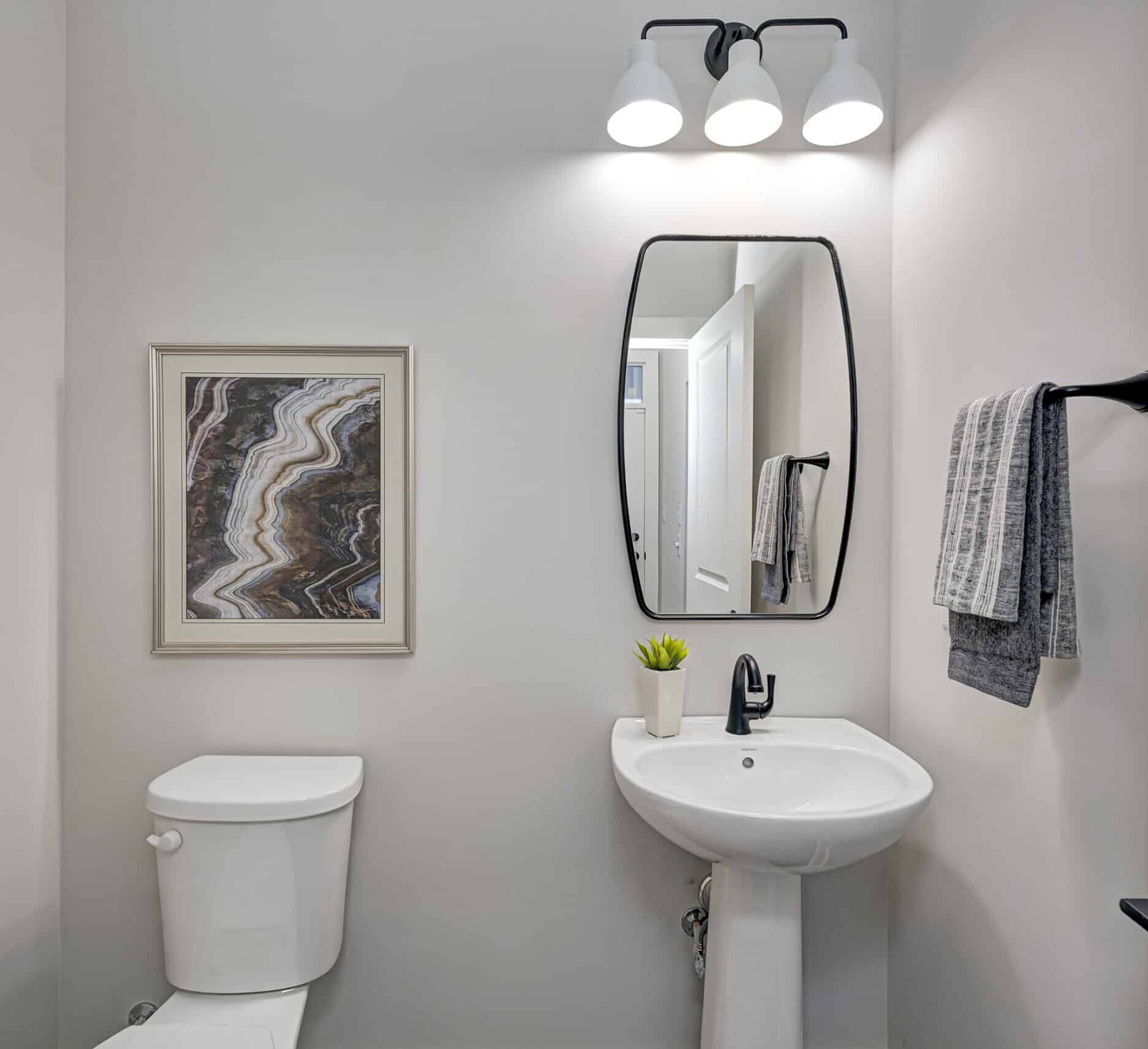 A custom bathroom in a new home with a toilet, sink and mirror.