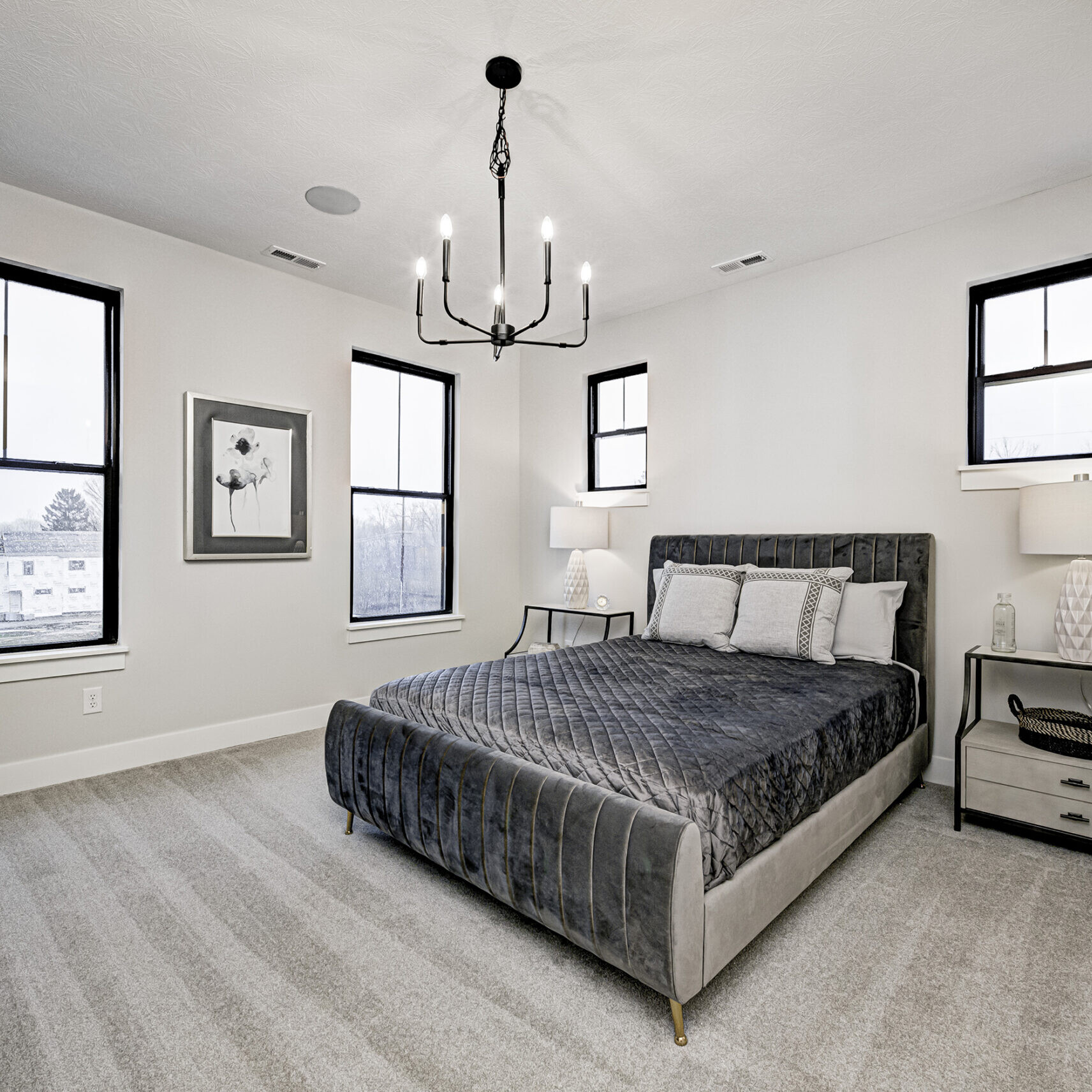 A bedroom with a large bed and a chandelier, found in Indianapolis Custom Homes.