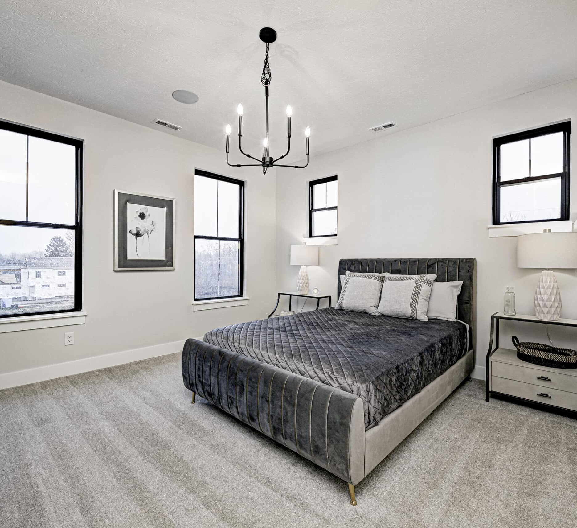 A bedroom with a large bed and a chandelier, found in Indianapolis Custom Homes.