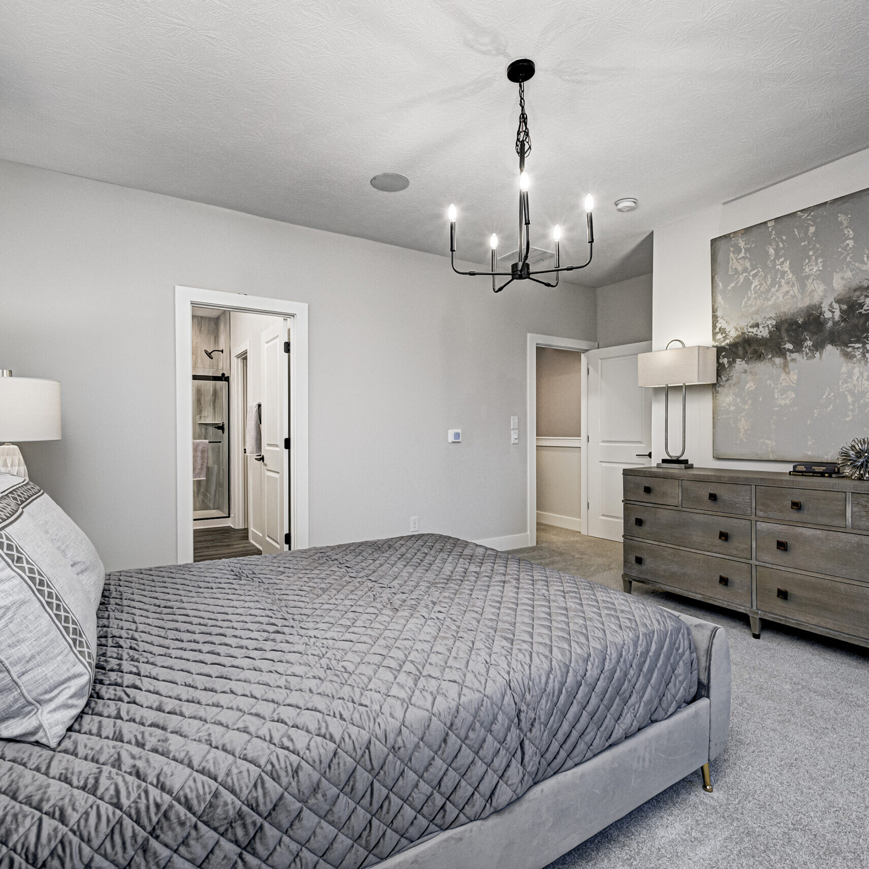 A gray bedroom featuring a bed and dresser.