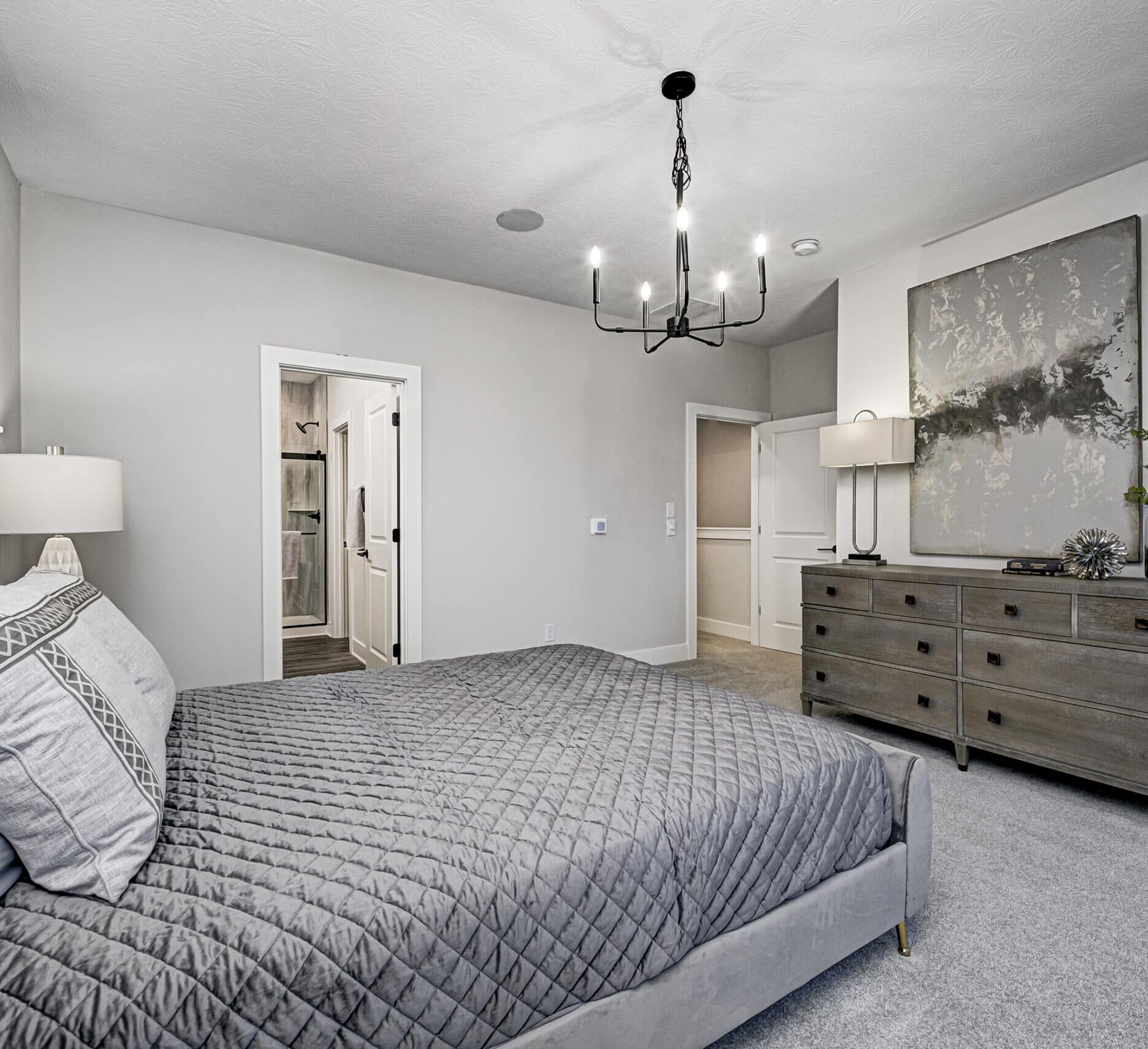 A gray bedroom featuring a bed and dresser.