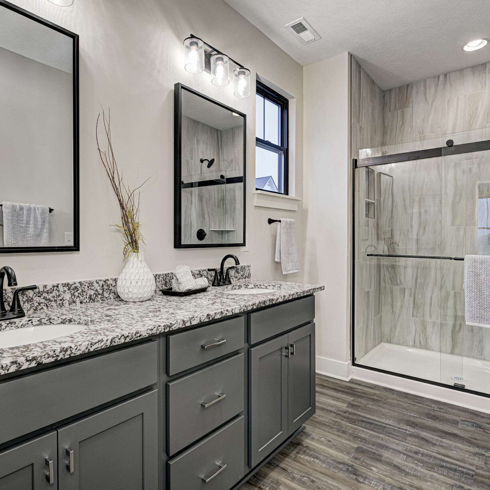 A bathroom with gray cabinets and granite counter tops, built by a custom home builder in Fishers, Indiana.