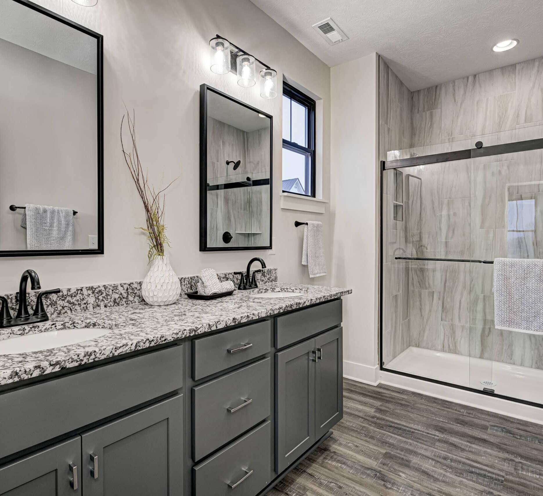 A bathroom with gray cabinets and granite counter tops, built by a custom home builder in Fishers, Indiana.